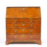 A GEORGIAN STYLE WALNUT BUREAU the fall front enclosing a fitted interior with drawers and pigeon