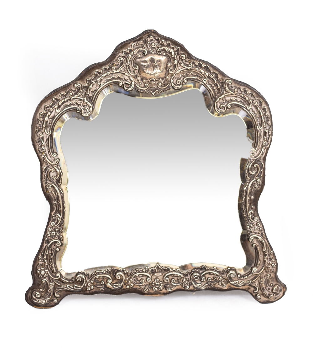 A VICTORIAN EMBOSSED SILVER MOUNTED DRESSING TABLE MIRROR with shaped and bevelled glass, 34cm