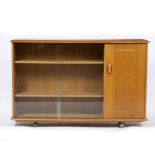 AN ERCOL STYLE SIDE CABINET with glazed sliding doors and single cupboard, all on easy glide