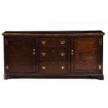 A 19TH CENTURY OAK DRESSER BASE with two panelled doors and three central drawers, on bracket