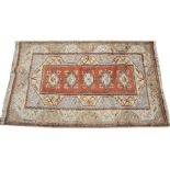 A TURKISH RED AND CREAM GROUND RUG with a banded border and five central motifs, 155cm x 263cm