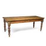 A LARGE PINE KITCHEN TABLE the planked top with cleated ends and on turned tapering legs, 212.5cm