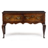 A GEORGE III OAK DRESSER BASE with two drawers and standing on cabriole legs terminating in club