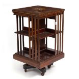 AN EDWARDIAN MAHOGANY ROTATING BOOKCASE with decorative inlay to the top in the form of dolphins, on