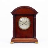 A LATE 19TH CENTURY MAHOGANY MANTLE TIMEPIECE with arching hood, fluted columns to either side of