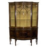 AN EDWARDIAN SERPENTINE FRONTED DISPLAY CABINET the upper section with twin glass shelves behind the