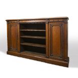 A LARGE OAK BOOKCASE with four open shelves flanked by two panelled cupboards with ebonised detail