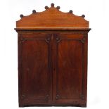 A VICTORIAN MAHOGANY PANELLED CUPBOARD the raised back decorated with roundels, the twin doors