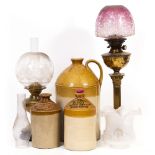 A BRASS OIL LAMP of Corinthian column form with cranberry glass tinted shade, 75cm high overall