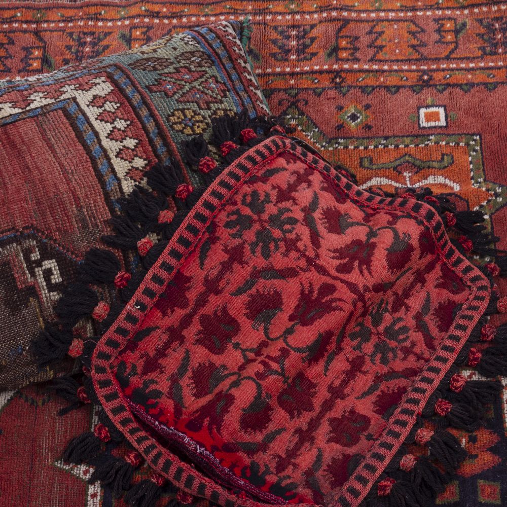 A DECORATIVE RED GROUND RUG 160cm x 132cm together with an old cushion constructed from an
