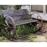 A WROUGHT IRON ROCKING GARDEN SEAT with styalised wheels to either side, 158cm wide x 92cm high