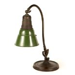 AN OLD BRASS DESK LAMP with circular base and adjustable arm supporting a green enamel decorated