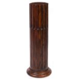 AN OAK TORCHIERE OR SCULPTURE PLINTH in the form of a classical fluted column base, 32cm diameter at