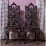 TWO POSSIBLY FRENCH CAST IRON HIGH BACKED CHAIRS with floral swag decorations to the back around a