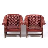 A PAIR OF RED LEATHER ARMCHAIRS of button back upholstered arms and seat, scroll cushions and square