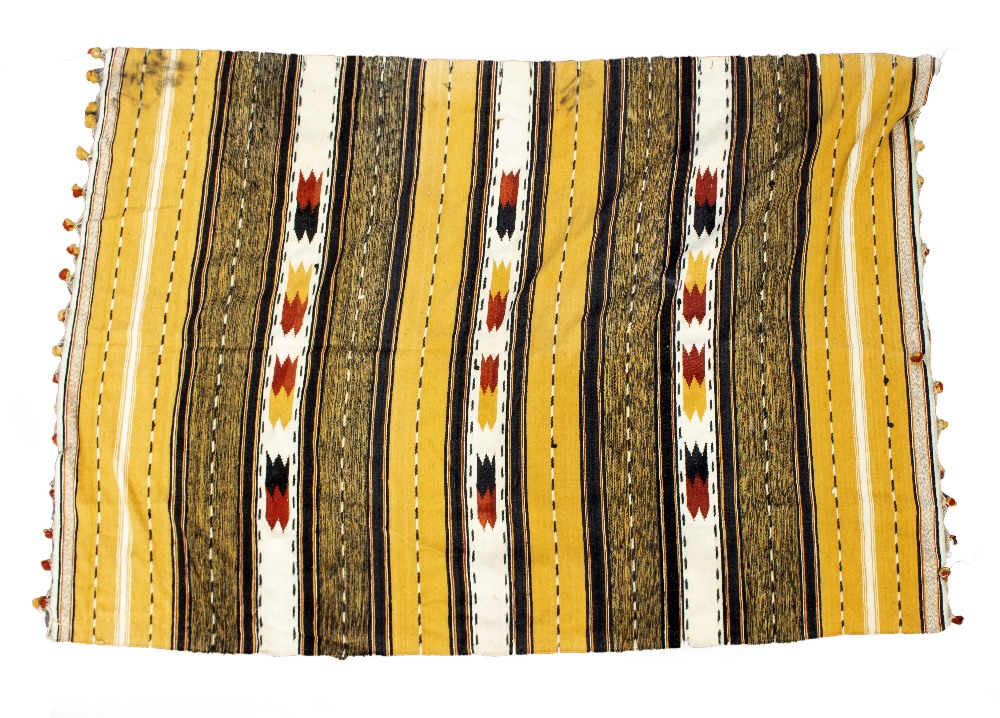 A CAMEL GROUND TRIBAL WOOLEN THROW with banded decoration and pompom tassels to the two ends,