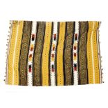 A CAMEL GROUND TRIBAL WOOLEN THROW with banded decoration and pompom tassels to the two ends,
