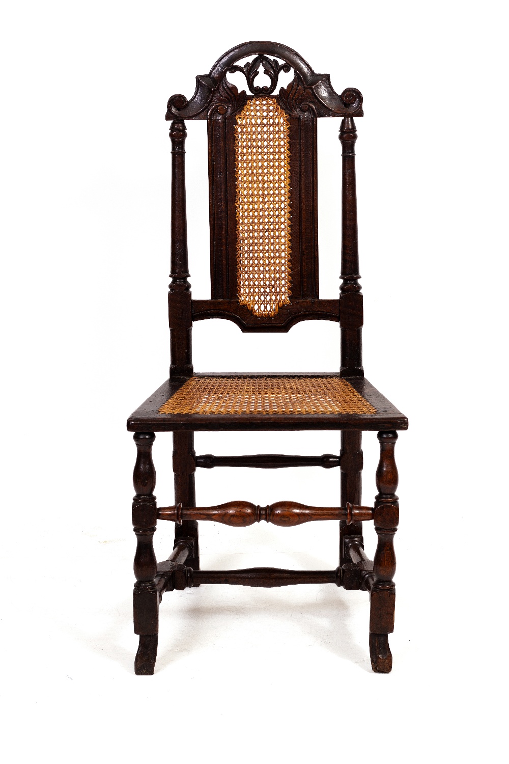 A CAROLEAN OAK SIDE CHAIR with arching pierced foliate crest, caned back and seat and turned legs