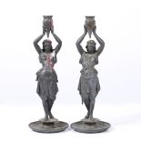 A PAIR OF SPELTER CANDLESTICKS in the form of classical maidens holding urns aloft each standing