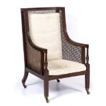 A 19TH CENTURY MAHOGANY WING BACK BERGERE ARMCHAIR with cane backed and sides, cream upholstered