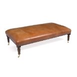 A MODERN TAN LEATHER UPHOLSTERED RECTANGULAR STOOL with turned tapering legs and brass casters,