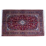AN ORIENTAL RED GROUND RUG with diamond decoration to the centre, floral field and triple banded