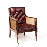 A 19TH CENTURY BERGERE ARMCHAIR with caned back and sides and red leather upholstered squab