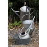 A GROUP OF THREE OLD GALVANIZED OLD WATERING CANS the largest three gallons in size and 50cm high