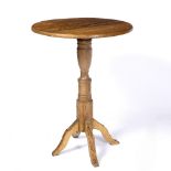 A PINE OR POSSIBLY CHESTNUT CIRCULAR OCCASIONAL TABLE with a turned stem and four carved legs,