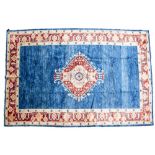 A BLUE GROUND AGHAN RUG with central motif to the plain field and within a triple banded floral