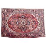 A MODERN ORIENTAL RED GROUND RUG with central stylised motif and triple banded border, 354 x 240cm