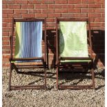 TWO HARDWOOD DECK CHAIRS one upholstered in leaf designed material, the other in coloured stripes,