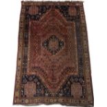 A RED GROUND ORIENTAL RUG with central diamond motif, stylised flowers and horses to the shaped