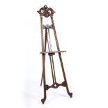 A VICTORIAN WALNUT GALLERY PICTURE EASEL with scrolling top and further carved decoration, 66cm wide