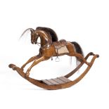 A MINIATURE CARVED HARDWOOD ROCKING HORSE with horse hair mane and tail and leather saddle, with