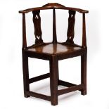 AN ANTIQUE PRIMITIVE OAK CORNER ARMCHAIR with pierce splats, panel seat and the reeded legs united