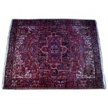 A RED GROUND HERIZ CARPET with central cross motif, stylised floral decoration to the field and with