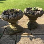 A PAIR OF CAST COMPOSITE GARDEN URNS with gadrooned bodies on turned bases, 48cm diameter x 36cm