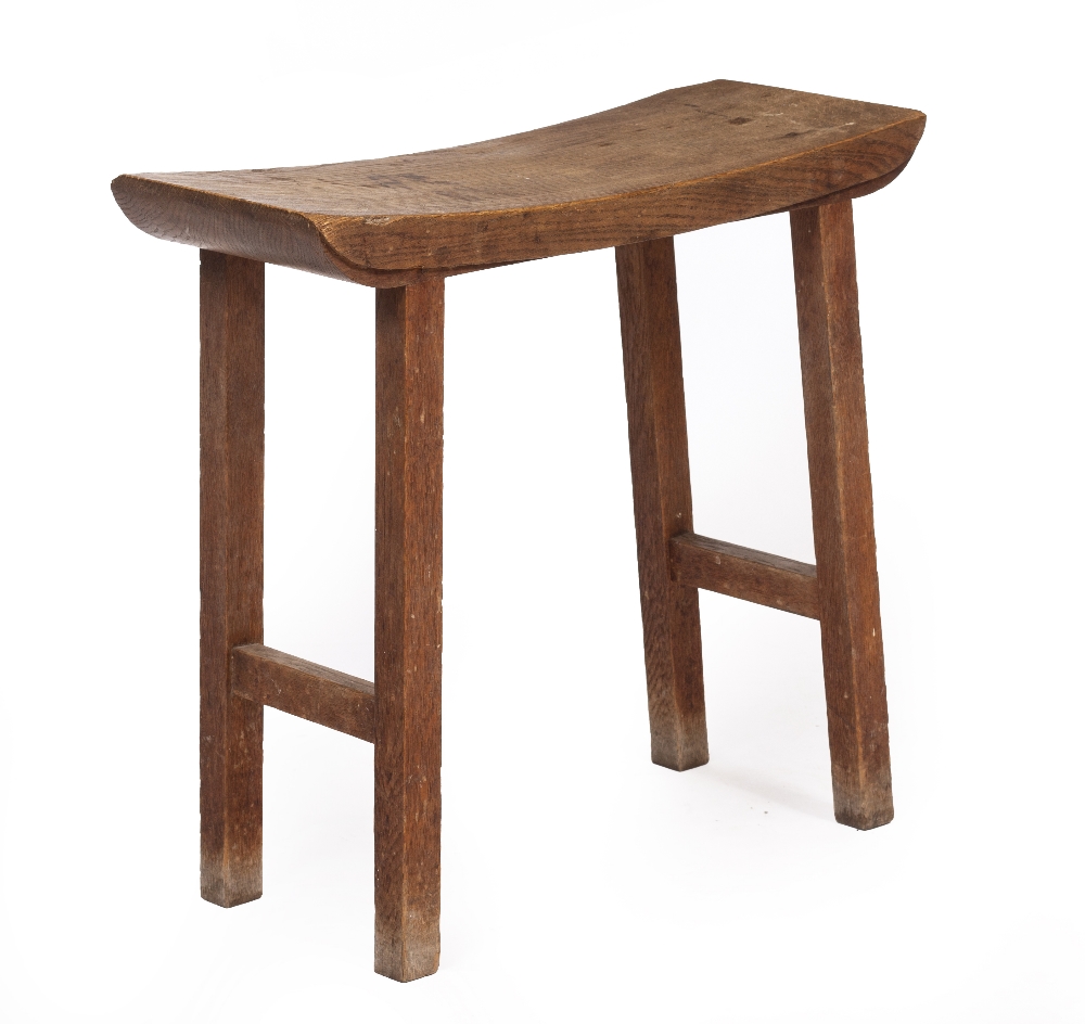 AN ARTS AND CRAFTS OAK STOOL with shaped top and square legs and united by stretchers at each end,