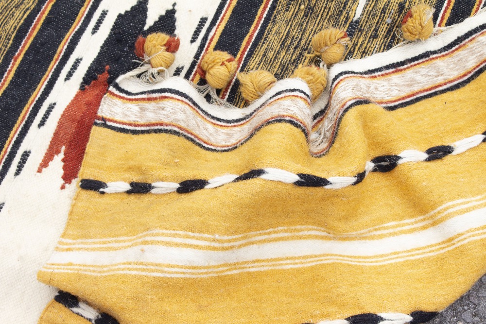 A CAMEL GROUND TRIBAL WOOLEN THROW with banded decoration and pompom tassels to the two ends, - Image 2 of 4