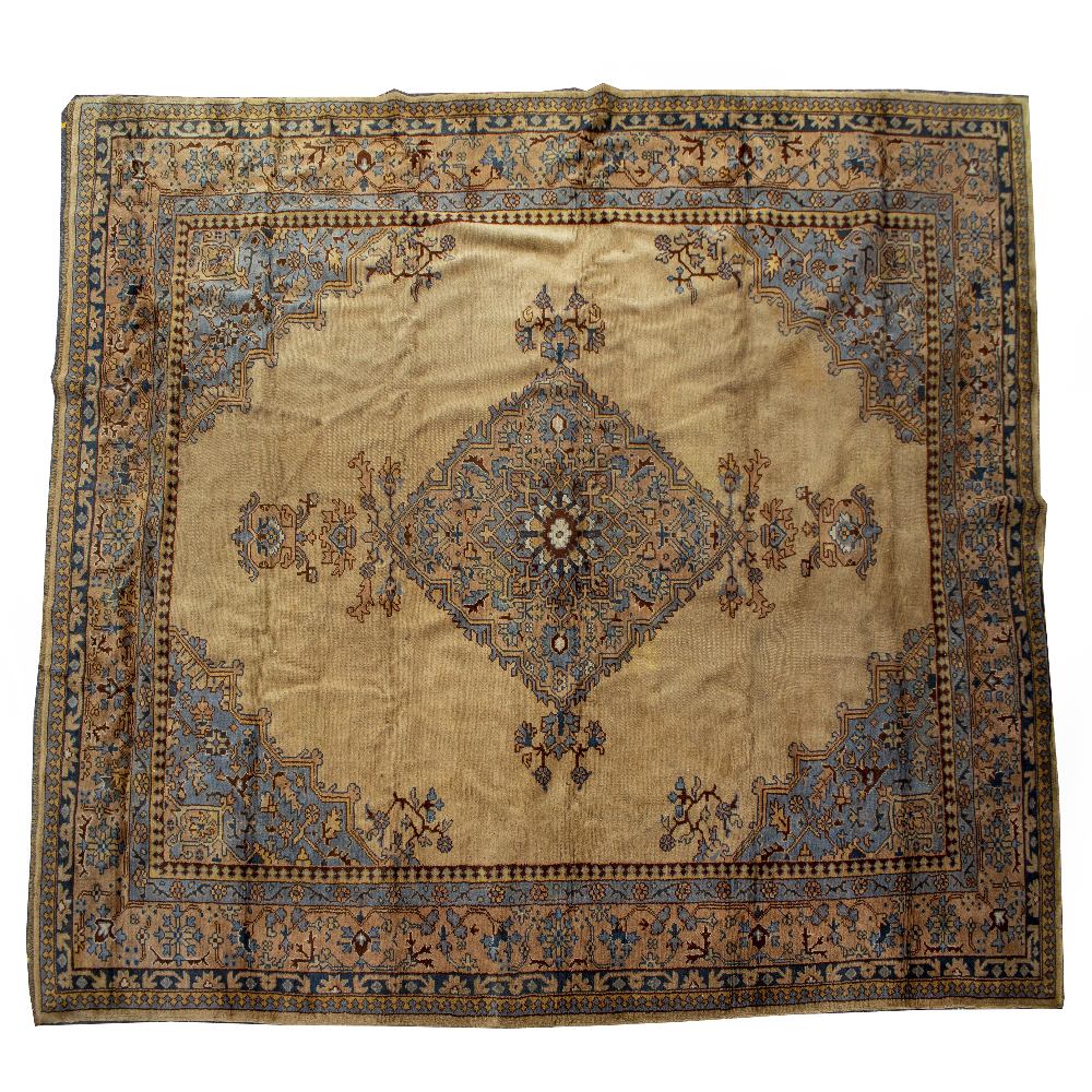 A CAMEL GROUND TURKEY RUG with diamond designs to the central field with bracketed corners and