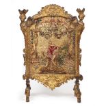 A DECORATIVE GILT FIRE SCREEN the finials in the form of female heads with plumed head dresses, with