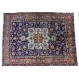 A DARK BLUE ORIENTAL RUG with yellow and red decorated motif to the centre of the floral ground