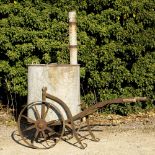 A 19TH CENTURY GALVANIZED ZINC WATER BARREL with down pipe connector and a wrought iron cart, 90cm