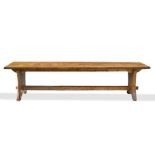 A LARGE PINE KITCHEN TABLE with plain rectangular plank top and shaped waisted end supports united