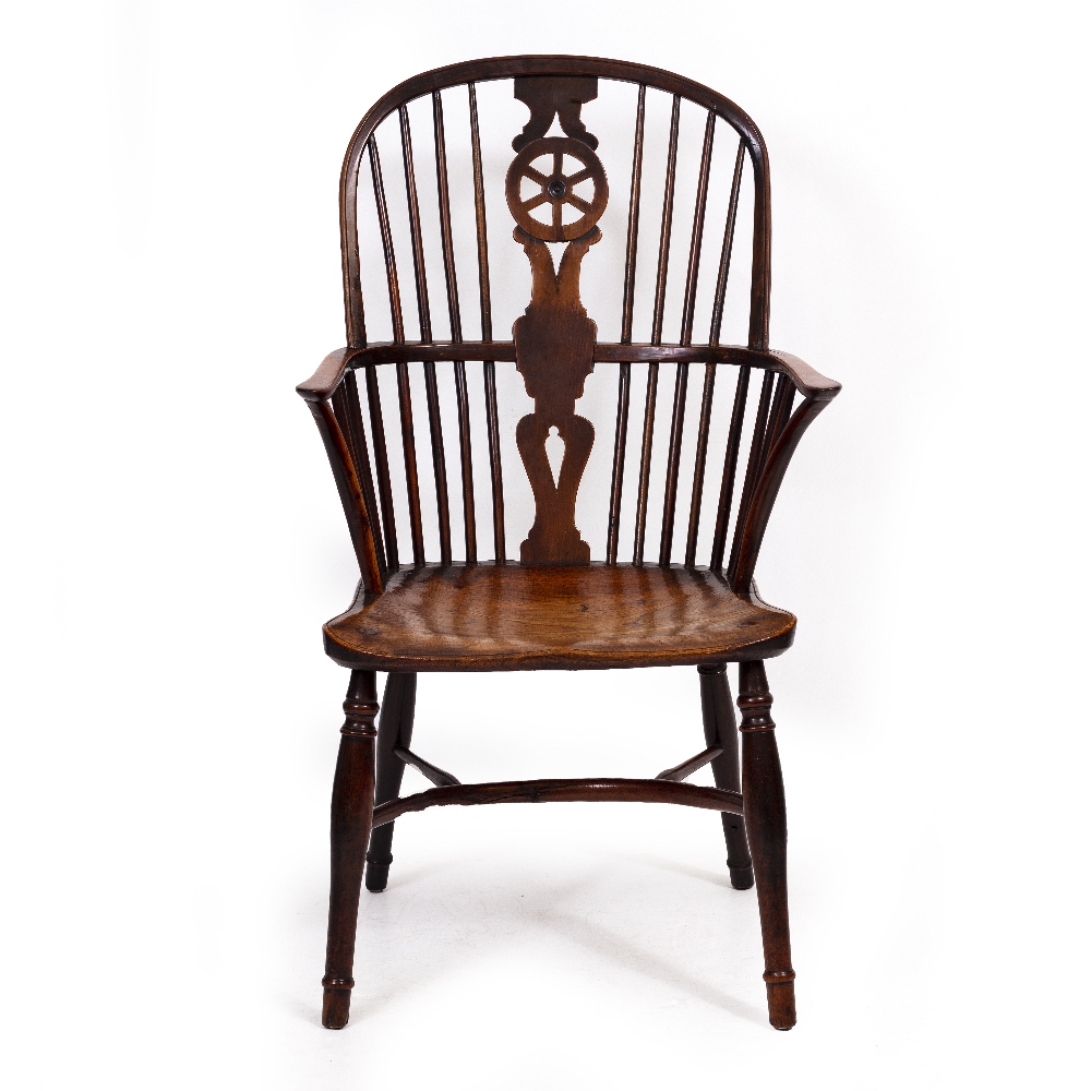 AN ANTIQUE YEW WOOD AND ELM WINDSOR WHEEL BACK ARMCHAIR with carved saddle seat and turned legs