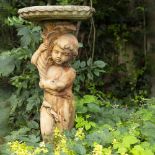 A CAST COMPOSITE GARDEN BIRD BATH the dish supported by a putti on a spreading square plinth base,