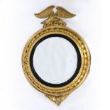 A REGENCY CIRCULAR GILT FRAMED CONVEX WALL MIRROR with eagle crest and black painted slip, 65cm wide
