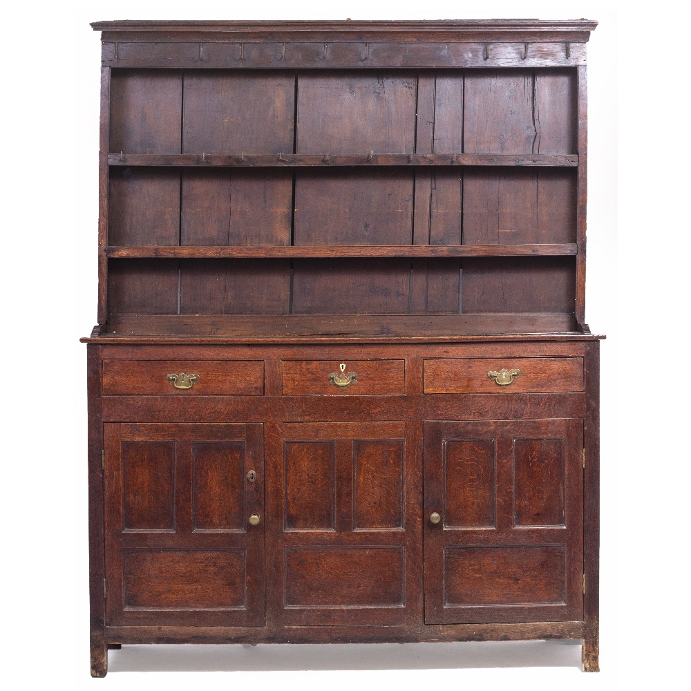 AN EARLY 19TH CENTURY OAK DRESSER with plate rack above, three doors and two panelled cupboard