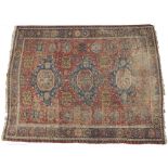 AN ANTIQUE ORIENTAL RED GROUND RUG with three diamond shaped motifs to the central field with